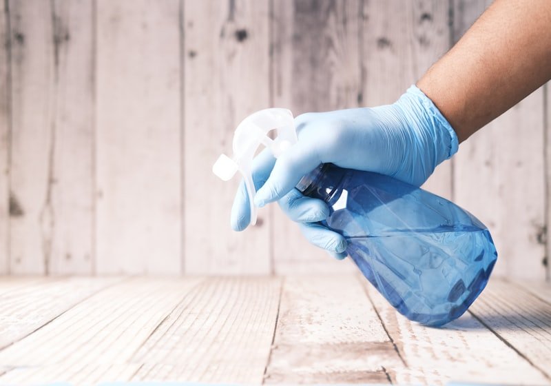 Gloved hand holding a cleaning spray bottle
