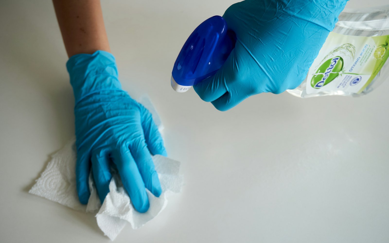 Cleaner wiping down a surface with cleaning spray