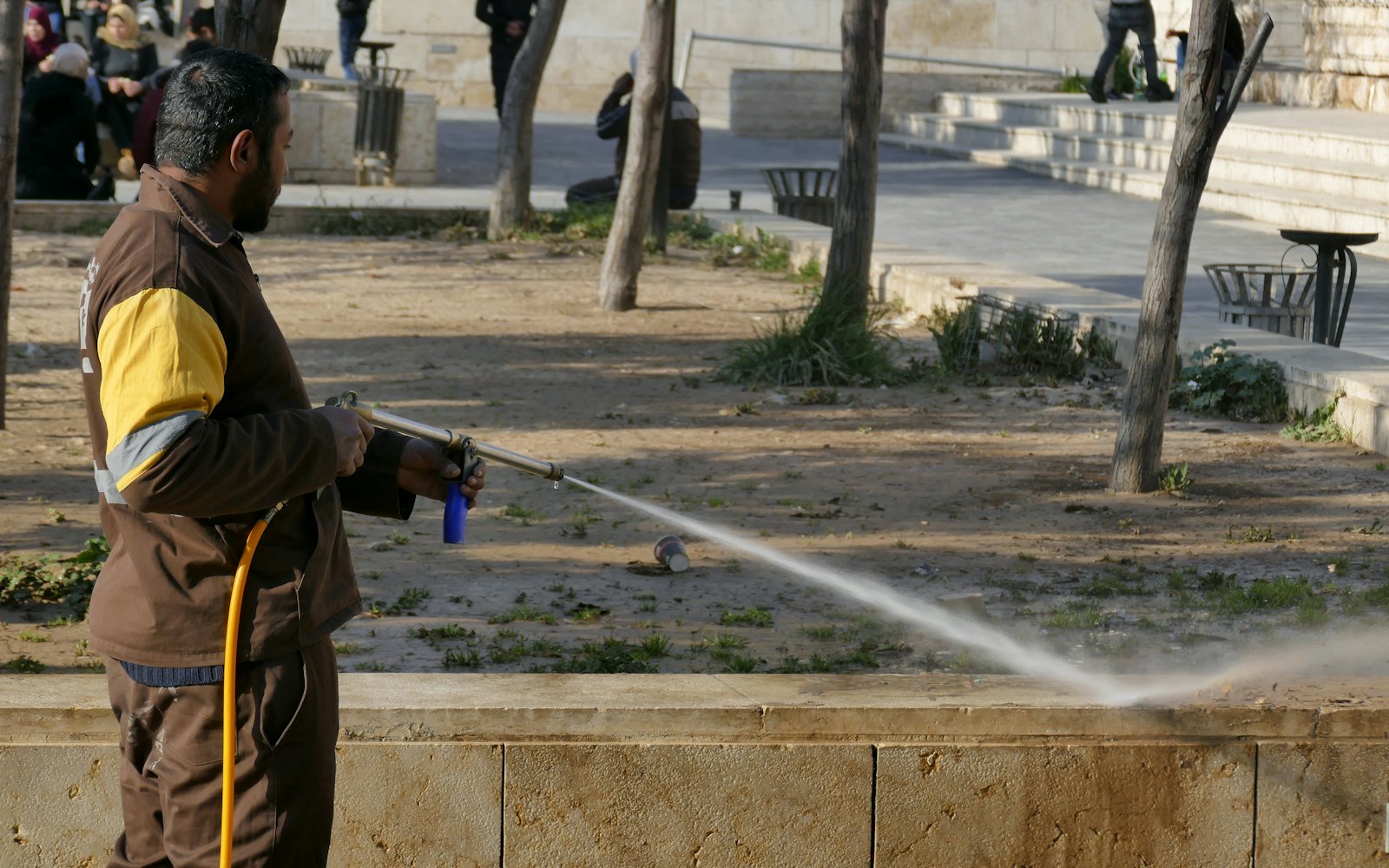 Worker pressure cleaning a paved outdoor walkway