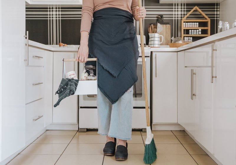 Cleaner with a broom in a tidy kitchen