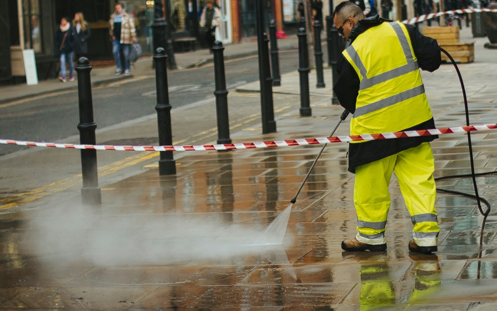 Operator pressure cleaning a paved outdoor surface